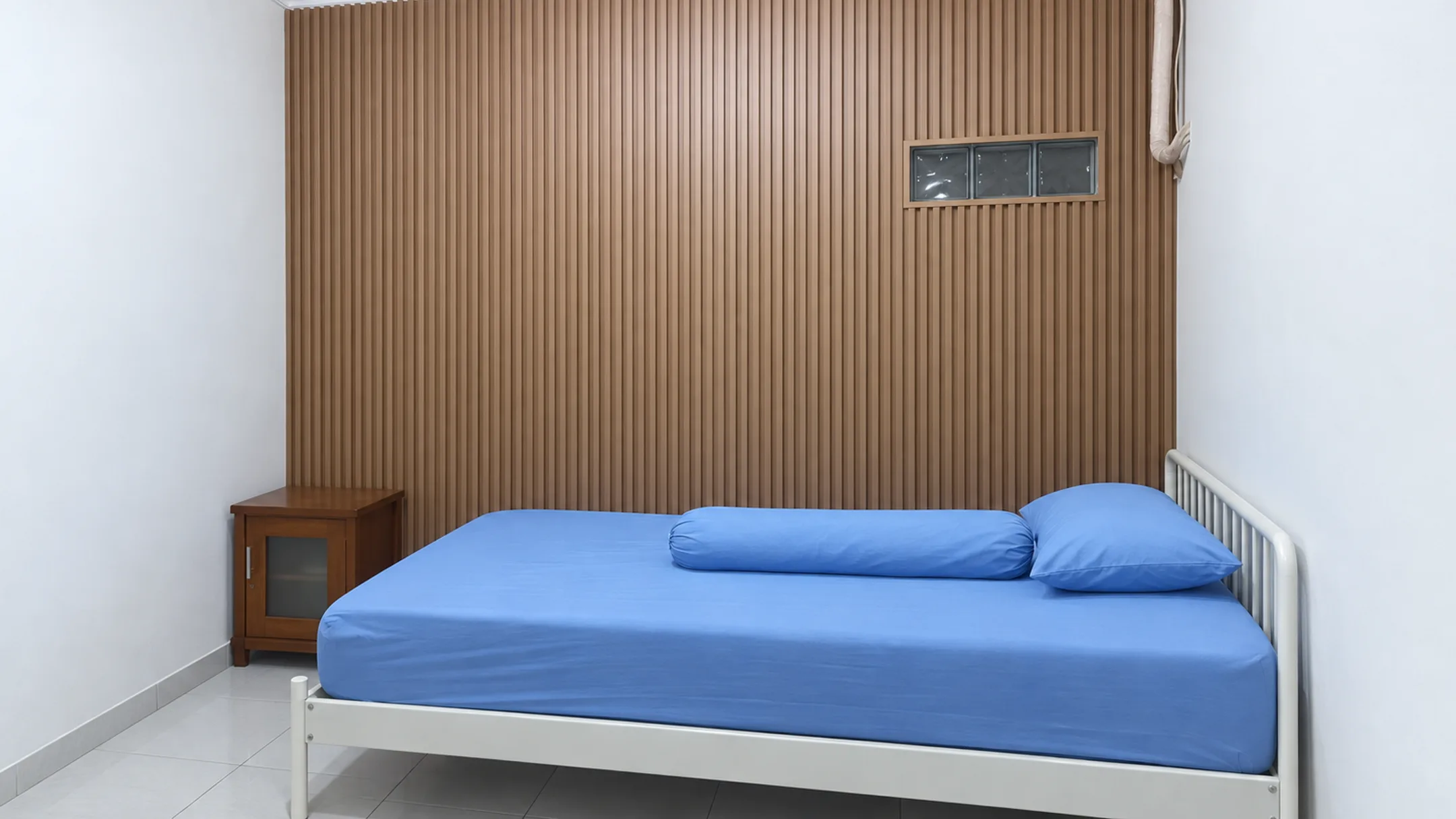 Foto pemasangan kisi-kisi WPC Champion motif kayu cokelat yang menutup seluruh dinding belakang ranjang di kamar tidur
